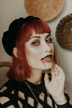A Woman Getting Ready For Halloween And Wearing Vampire Makeup