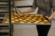 © Liliya Rodnikova/Stocksy - faceless baker put backing pan with macaroons on tray