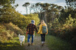 © Daniel Gonzalez/Stocksy - Couple walking with dog in park