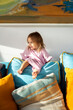© Santi Nuñez/Stocksy - Cute little girl sitting on the sofa.
