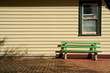 © Rowena Naylor/Stocksy - Bright green bench against timber building