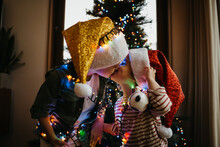 Two Kids Kissing In Front Of The Christmas Tree