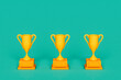 © Giada Canu/Stocksy - three Yellow trophy on green background