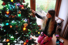 A Girl Decorating A Christmas Tree On A Chilly Day