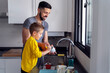 © Albert Martinez/Stocksy - son helping his daddy clean up the dishes after lunch