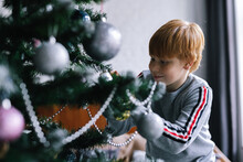 Little Kid Concentrating On Decorating Christmas Tree