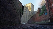 Side Movement Of Large Cathedral From Low Angle On Cobbled Alley Way In Historic City Of York.