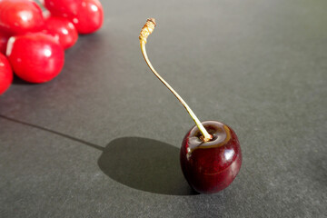 Wall Mural - red cherries with a shadow, standing on a dark background with red berries, side view.