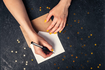 Wall Mural - A woman writes plans for 2022 on black background top view