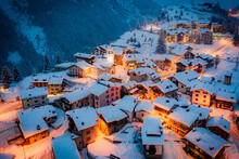 Christmas Lights On Mountain Houses And Chalets Covered With Snow At Dusk, Pianazzo, Madesimo, Valle Spluga, Valtellina, Lombardy, Italy