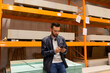 © Ivan Traimak - a man in a hardware store sits on the shelves with drywall and looks at the phone, the concept of repair and construction of a house, the choice of materials for construction