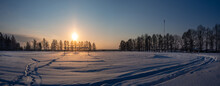 Snow Sparkles At Snowy Football Field In Winter Evening. Silhouette Of Trees In Rays Of The Setting Sun. Place For Your Text. The Cold Season.