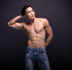 Wall Mural - Muscular bodybuilder Asian man doing posing over black background