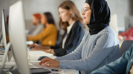 Fototapete - Curious Female Muslim Student Wearing a Hijab, Studying in Modern University with Diverse Multiethnic Classmates. College Scholars Work in College Room, Learning IT, Programming or Computer Science.