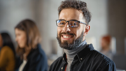 Poster - Portrait of a Handsome Smart Male Student, Studying in University, Fondly Smiling on Camera. He Wears Glasses and Has a Beard and Short Curly Hair. Works on Computer in College.