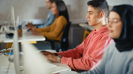 Fototapete - Handsome Smart Male Student, Studying in University with Diverse Multiethnic Classmates. He Works on Desktop Computer in College. Applying His Knowledge to Acquire Academic Skills in Class.