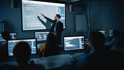 Fototapete - Teacher Giving Computer Science Lecture to Diverse Multiethnic Group of Female and Male Students in Dark College Room. Projecting Slideshow with Programming Code. Explaining Information Technology.