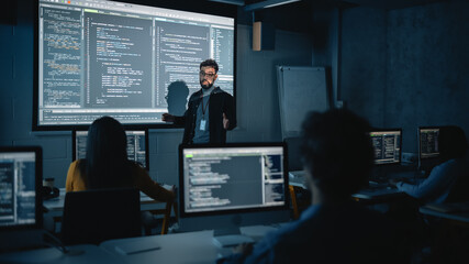 Fototapete - Teacher Giving Computer Science Lecture to Diverse Multiethnic Group of Female and Male Students in Dark College Room. Projecting Slideshow with Programming Code. Explaining Information Technology.