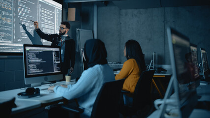Fototapete - Teacher Giving Computer Science Lecture to Diverse Multiethnic Group of Female and Male Students in Dark College Room. Projecting Slideshow with Programming Code. Explaining Information Technology.