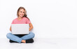 © luismolinero - Young Russian girl with a laptop sitting on the floor isolated on white background laughing