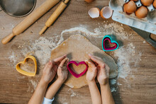 Top View Of Little Girl With Parent Cutting Heart Shape Cookies From Rye Dough