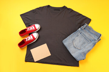 Wall Mural - Blank t-shirt, jeans, sneakers and carton sheet on yellow background