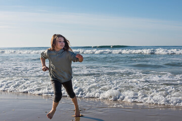 Wall Mural - pretty girl full of vitality running and jumping on the sunny beach