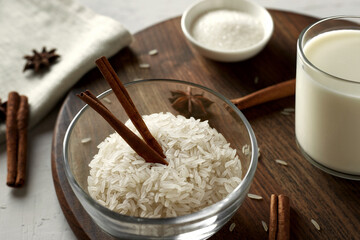 Wall Mural - Glass bowl with rice grits and cinnamon sticks. Ingredients for rice milk porridge - rice, milk, sugar, cinnamon sticks, anise stars. Selective focusing.