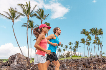 Fitness exercise runners couple running lifestyle. Healthy people jogging together in summer park outdoor, athletes training cardio during Hawaii travel vacation.