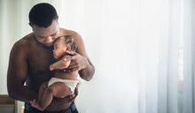 African Father Holding His Daughter, 3 Month Old Baby Newborn Which Is Protection And Happy In A White Bedroom, Concept To African Family And Newborn
