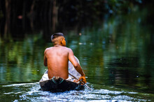 Native Tribal Man In Amazonia Rainforest In Handmade Boat