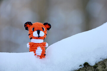 Wall Mural - Knitted toy tiger in snow in a forest. Background for greeting card of New Year celebration, Year 2022 of the tiger according to the Chinese calendar