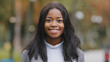 © Yuliia - Young positive girl turns looking at camera businesswoman smiling with white teeth attractive happy african american woman outdoors close up adult pensive millennial lady in park portrait female face
