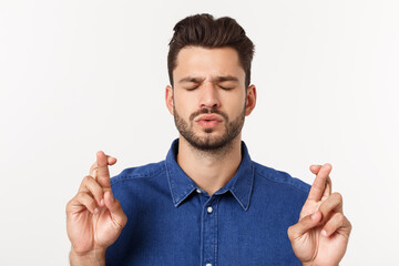 Wall Mural - A portrair of a young man with crossed fingers and closed eyes praying for risky business.