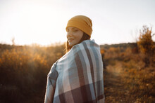 Outdoor Woman With A Blanket On Her Shoulders Smiles Enjoys Sunset In Autumn Nature Meadow At Sunset In Nature. Hope, Mental Strength Concept.
