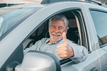 Happy Owner Looking At The Camera With Happy Face And Thumbs Up. Handsome Bearded Mature Man Sitting Relaxed In His Newly Bought Car Looking Out The Window Smiling Joyfully. One Old Senior Driving 