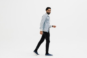 Full length side shot of handsome beard man smiling and walking, isolated on white background