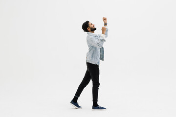 Indian handsome young man in jeans shouting for joy raising his hands above his head