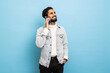 Young indian man talk to mobile phone on blue background