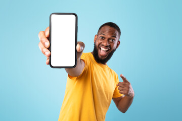 Poster - Mobile app advertisement. Excited black man pointing at smartphone with empty screen, mockup. Space for ad or website