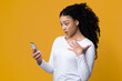 © Prostock-studio - Shock Content. Dazed African American Woman Looking At Smartphone Screen