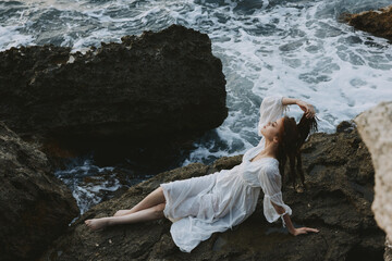 Poster - A woman in a white dress barefoot lies on a stone hold by her hair