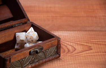 Wall Mural - Selective focus on set of role playing white dices lie in storage box on gaming table made of wood, banner: concept for role-playing games with place for text, crop, side view