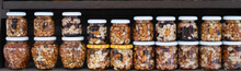 Various Nuts In Honey. A Stand With Products In The Street Market. Cashews, Walnuts, Almonds, Hazelnuts And Other Nuts In Honey Or Syrup In Jars.