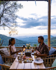 Wall Mural - dinner in the mountains of Chiang Mai Thailand, table bbq, couple man and woman using kitchen tongs grilling beef and bacon on the grill plate. Eating Korean Barbecue buffet in the restaurant. 