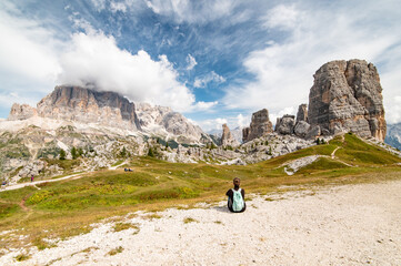 Young sport woman sitting and looking at Cinque Torri and Tofane Tofana di Rozes seen from Rifugio Scoiattoli (refuge). Dolomites, Trentino Alto Adige region, South Tyrol, Italy, Europe.