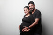 Loving and caring husband of Indian ethnicity touches the tummy of his wife expecting a baby