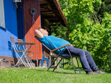 Fototapeta Na drzwi - A man enjoying sun on summer day in front of his cottage