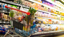 A Shopping Cart With Grocery Products In A Supermarket