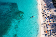 View From Above, Aerial View Of An Emerald And Transparent Caribbean Sea With A White Beach Full Of Beach Umbrellas And Tourists Who Relax And Swim. Cabbage Beach, Paradise Island, Bahamas